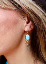 Close-up of a woman wearing a turquoise earring with a blurred background